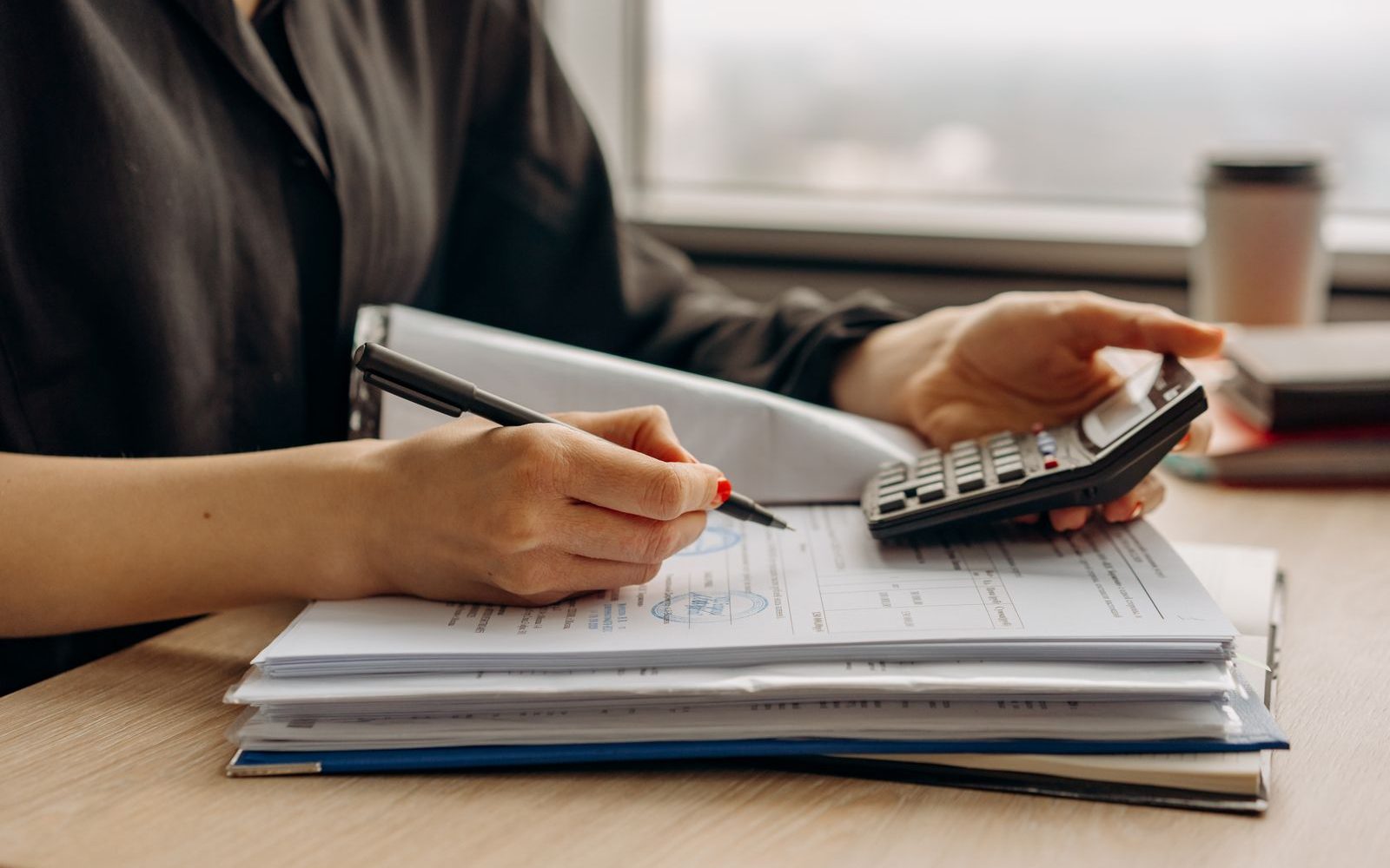 Hands working through property figures with a calculator and a stack of documents