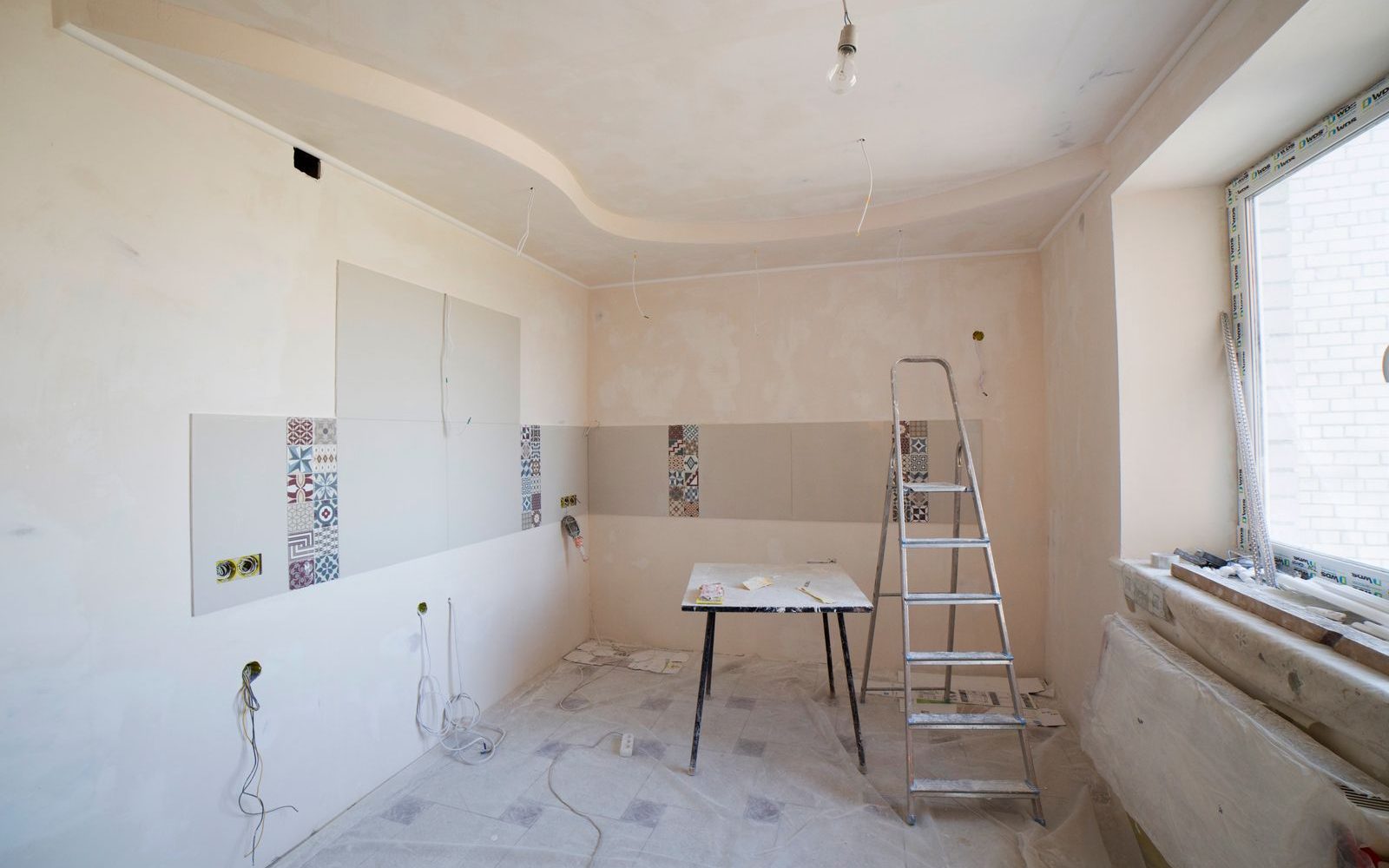 A room part-way through renovation, with a stepladder and tiling in progress
