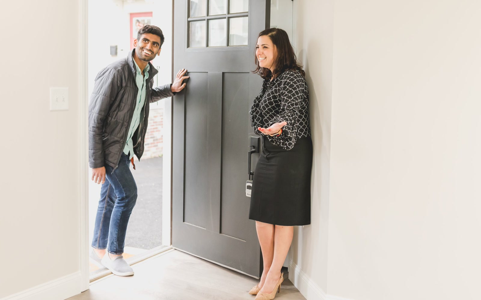 A real estate agent welcoming a visitor at the front door of a home
