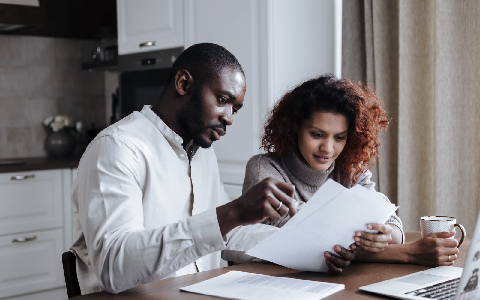 A couple reviewing loan documents together at their kitchen table