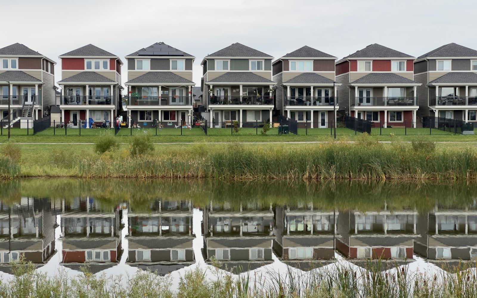 A row of new single-family homes reflected in a pond