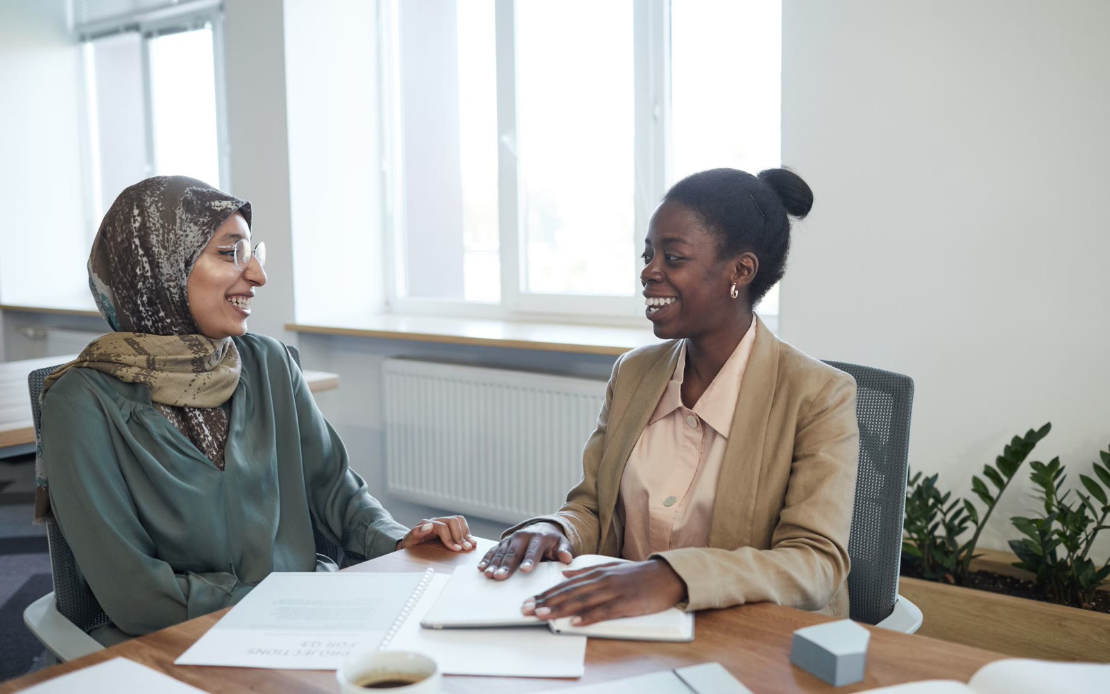 Two women at a desk going over papers together, both smiling