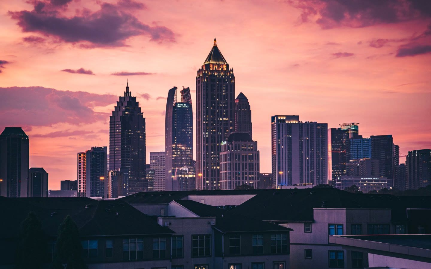 The Midtown Atlanta skyline at dusk, seen over rooftops