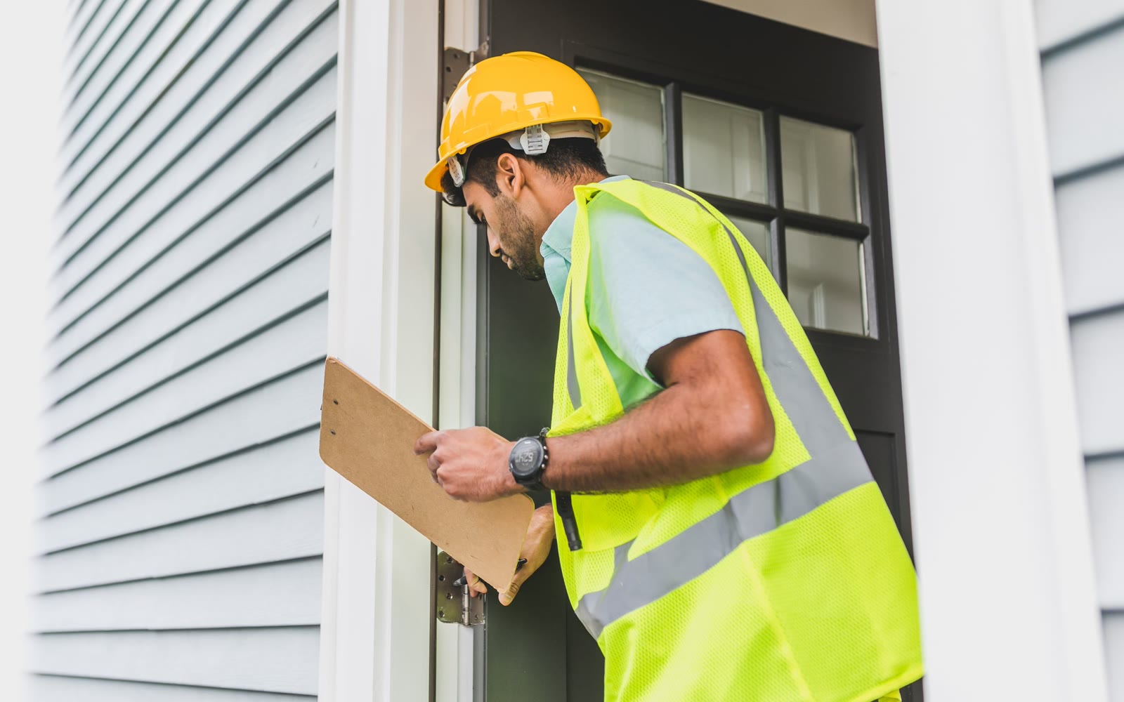 An inspector with a clipboard at a front door